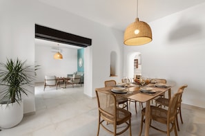 A dining area with a long table, chairs, and a hanging light fixture. - Villa Roseta by Escape Home (Puerto del Carmen)