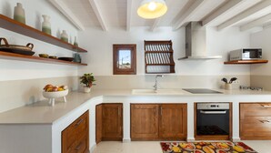 A kitchen with wooden cabinets, a microwave, a sink, and a hanging light fixture. - Villa Roseta by Escape Home (Puerto del Carmen)