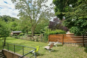 Un espace extérieur verdoyant, avec une clôture en bois, un banc et un escalier menant à un bâtiment.