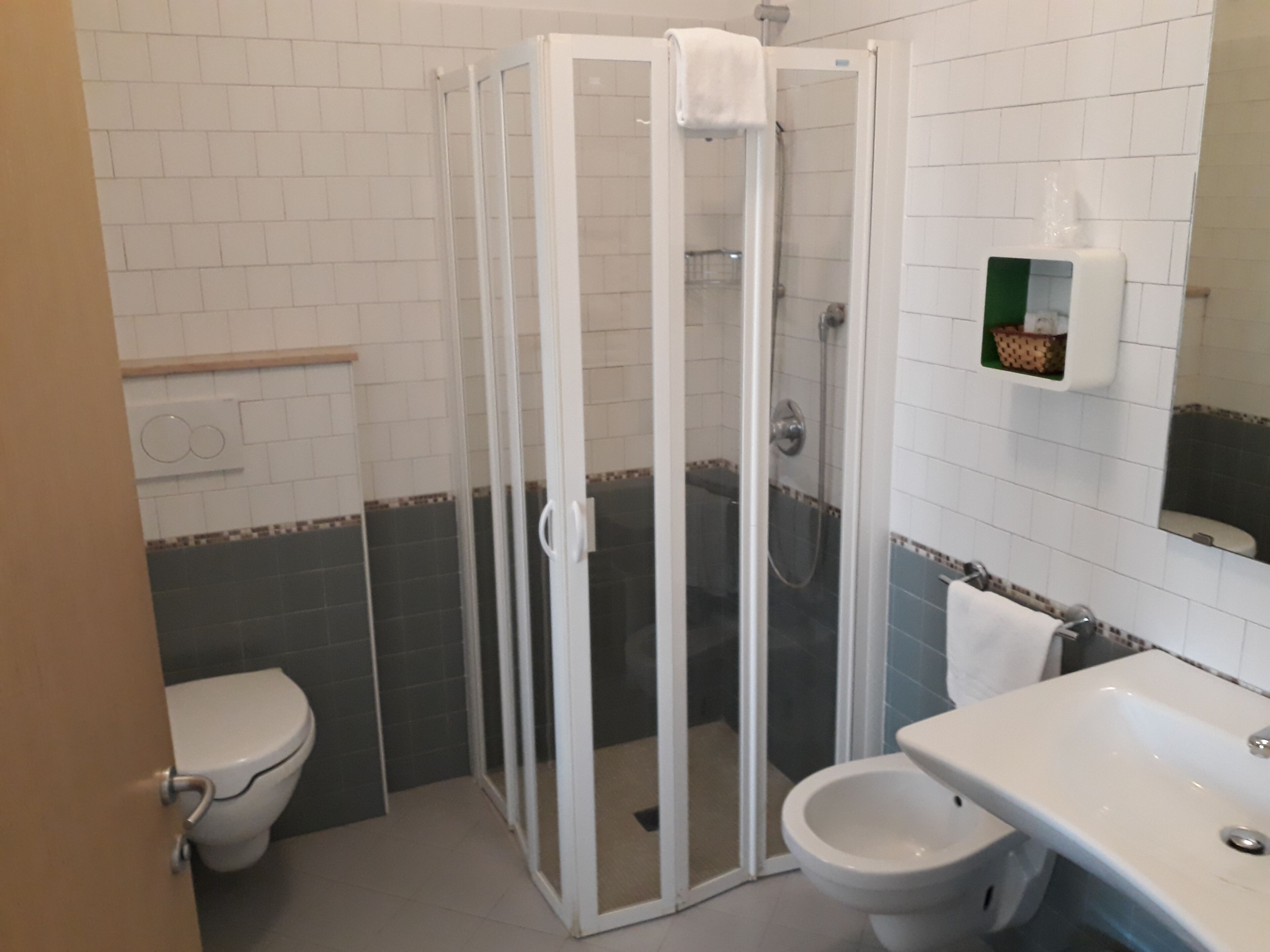 A bathroom with a glass-enclosed shower, a toilet, and a sink.