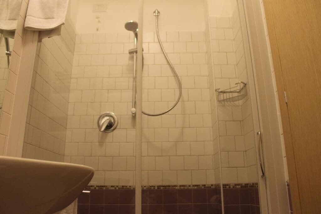 A shower with a glass door, a towel rack, and a shower head.