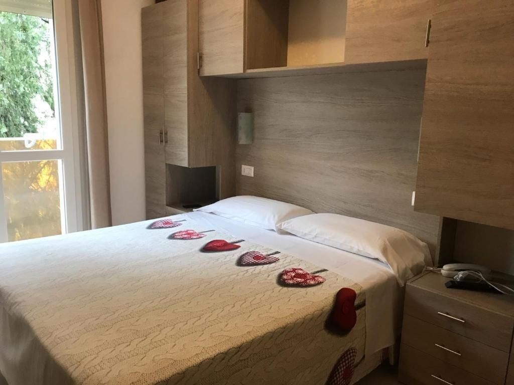A bedroom with a bed, a nightstand, a wardrobe, and a window.