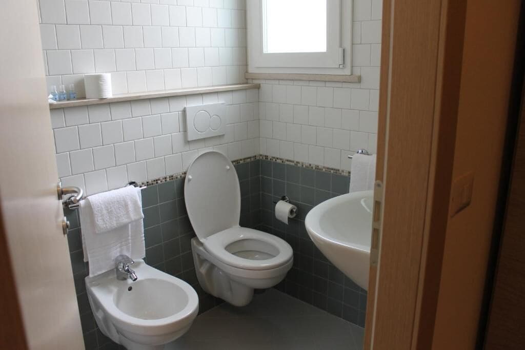 Une salle de bain avec deux toilettes, un lavabo et une fenêtre.
