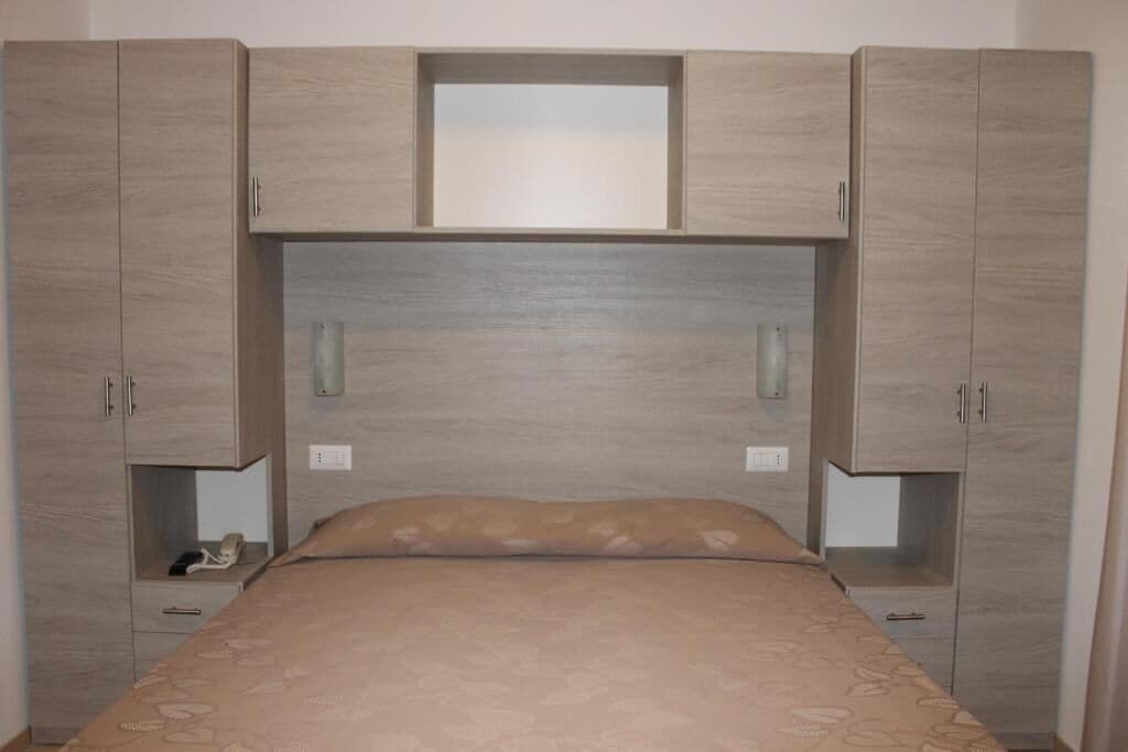 Un dormitorio con cama, cabecera y armarios empotrados.