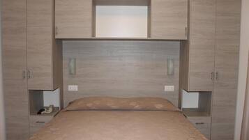 A bedroom with a bed, a headboard, and built-in wardrobes.