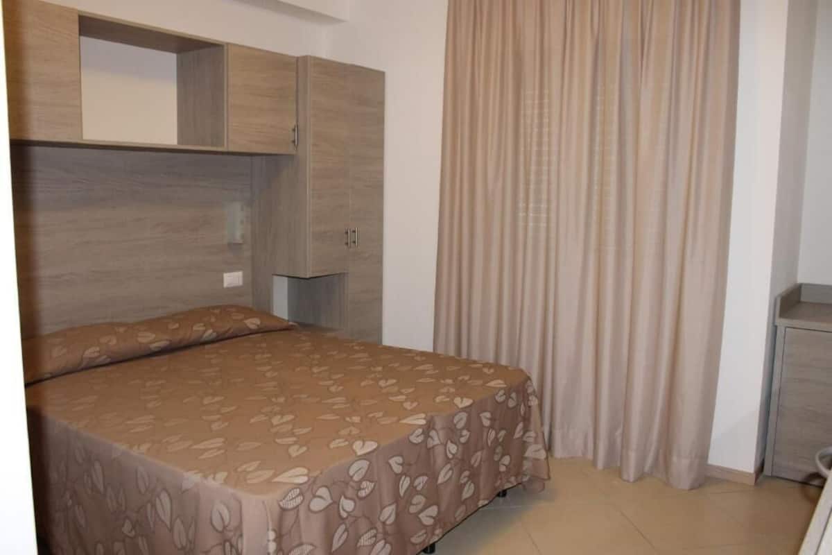 Um quarto com uma cama, um guarda-roupa e uma cortina.