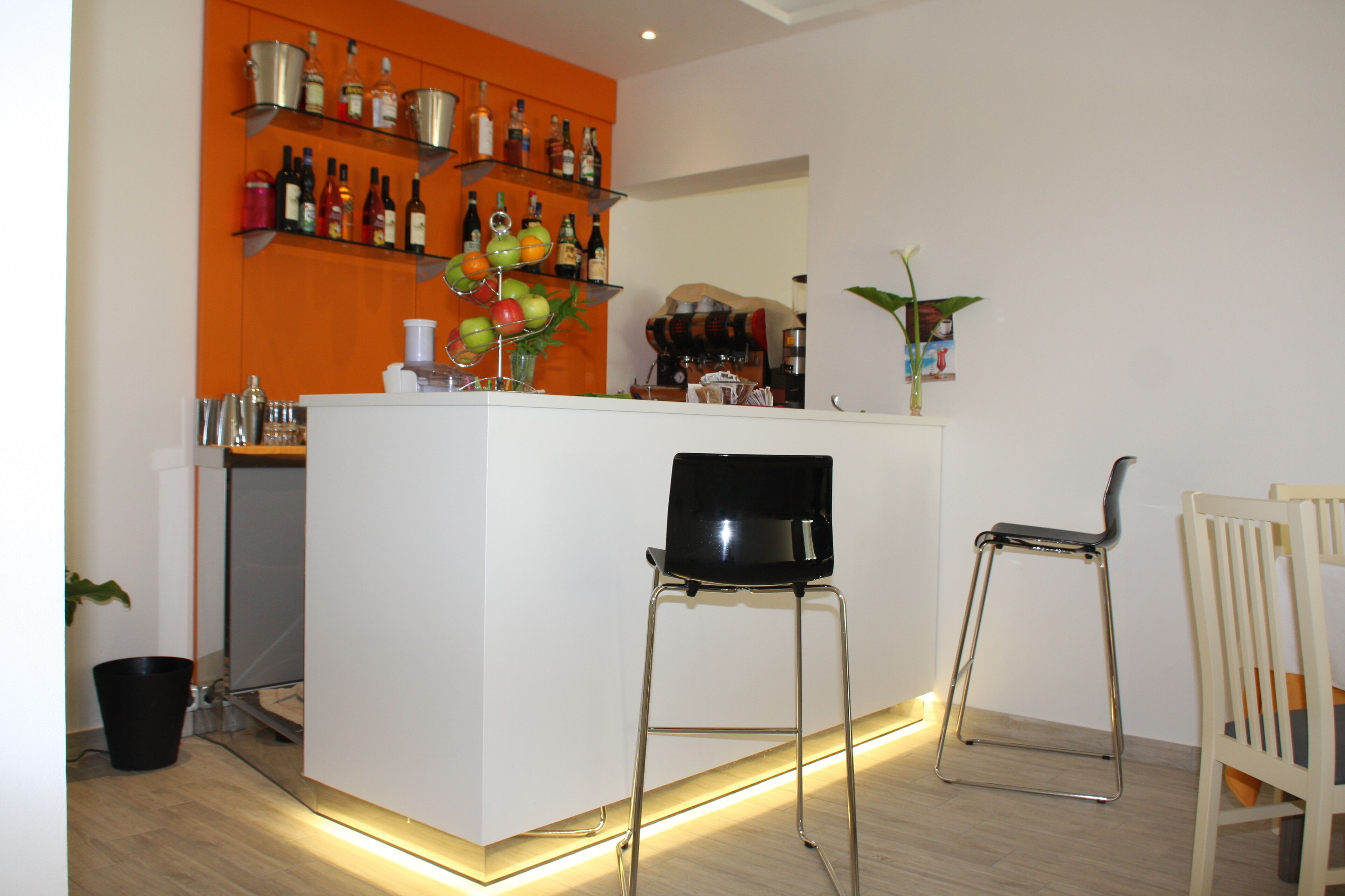 Eine moderne Küche mit einer zentralen Kochinsel, einer Bar mit Flaschenregalen und zwei Barhocker.