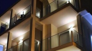 Un hotel de varios pisos con balcones, ventanas amplias y mobiliario exterior.