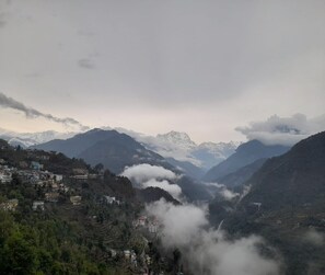Un paysage montagneux avec une vallée, des maisons et des sommets enneigés.