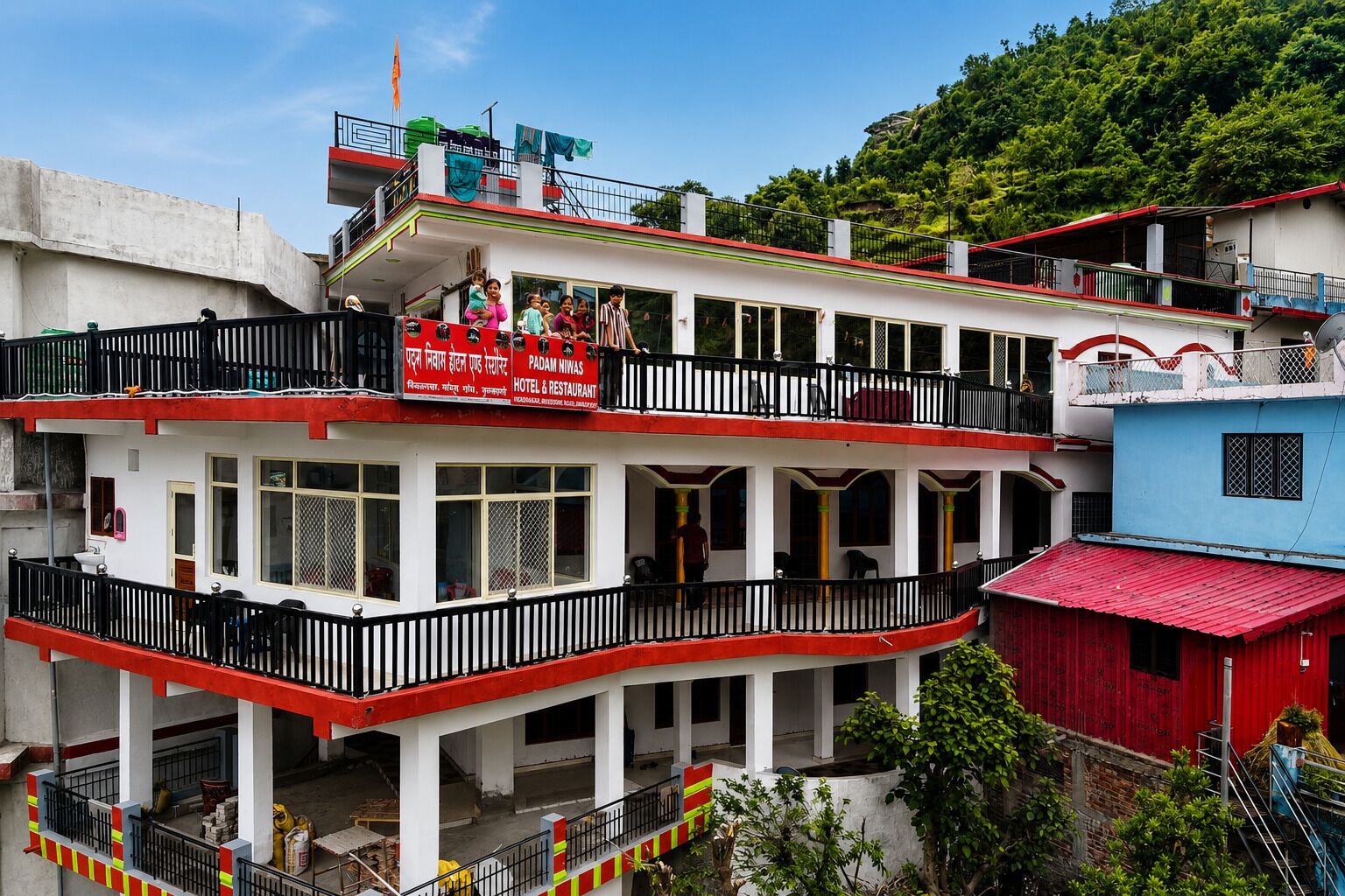 A multi-story hotel with balconies, a red and white facade, and a sign indicating it is a hotel and restaurant.