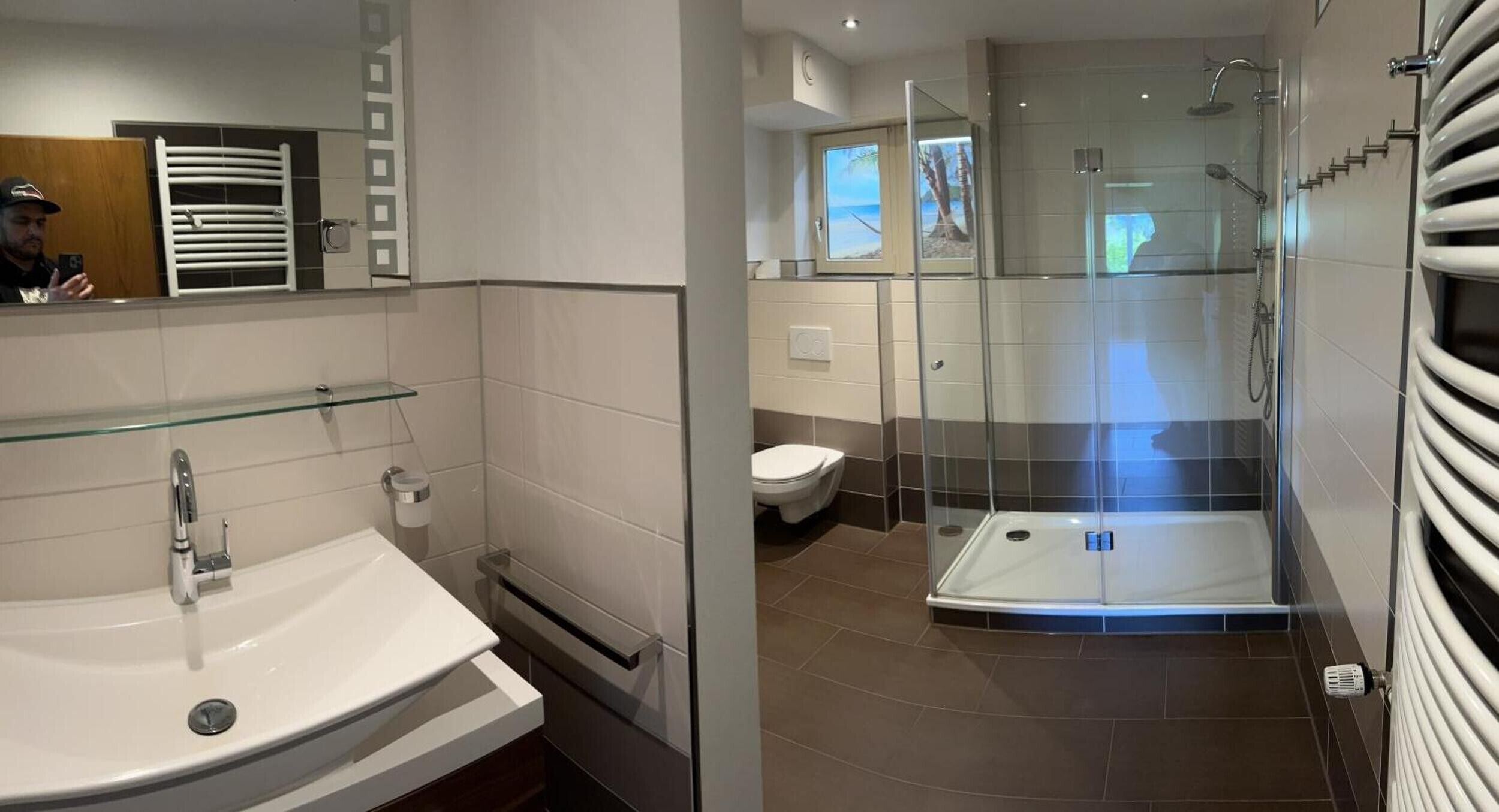 Een moderne badkamer met een douchecabine van glas, een witte wastafel en toilet.