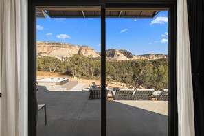 Ein Zimmer mit einer Schiebetür und Zugang zu einer Terrasse mit Liegestühlen und einem Pool.