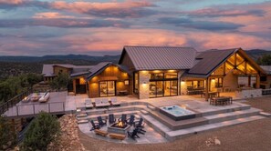 Ein modernes Haus mit Terrasse, Sitzgelegenheiten im Freien und einem Whirlpool.