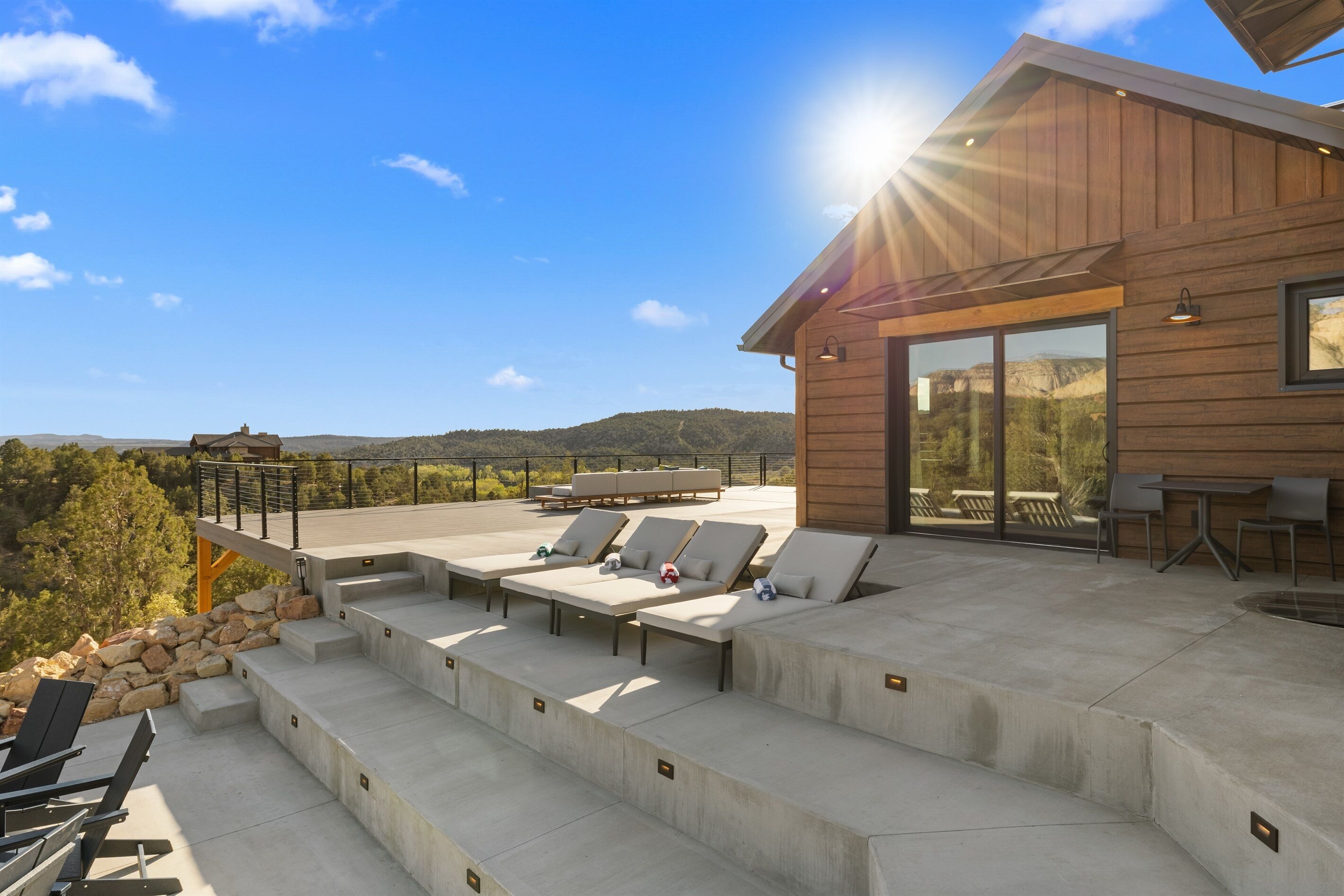 Un área de descanso al aire libre moderna con escalones de concreto, sillones y una mesa.