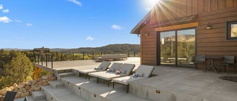 Un área de descanso al aire libre moderna con escalones de concreto, sillones y una mesa.