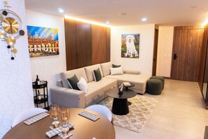 A modern living room with a sofa, coffee table, and wall art. - The Art of Rest: Designer Suite with Luxury Linens & Smart Home Features (Cuenca)