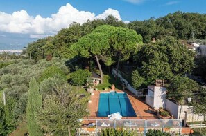 A residential property with a swimming pool, surrounded by dense trees and a view of the sea. - [TUSCANY]Villa with Pool, Jacuzzi and Gym (Serravalle Pistoiese)