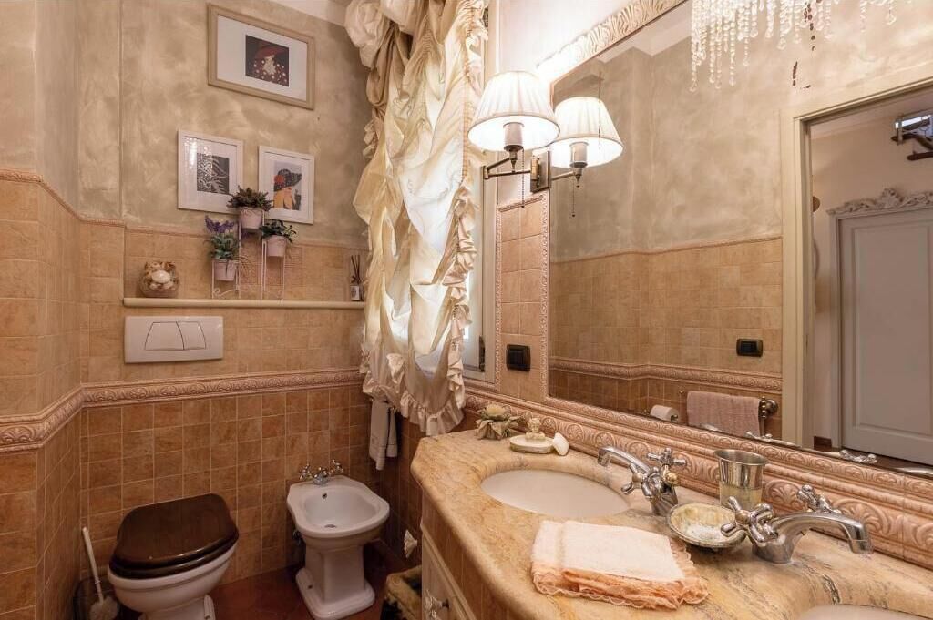 A bathroom with a toilet, bidet, sink, and mirror.