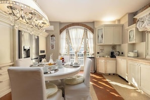 A dining area with a round table, chairs, a chandelier, and a view through a window with curtains. - [TUSCANY]Villa with Pool, Jacuzzi and Gym (Serravalle Pistoiese)