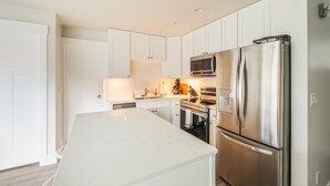 A modern kitchen with white cabinetry, stainless steel appliances, and a marble countertop. - Experience luxury in this 800 sq. ft. King bed ADU in Downtown Coeur d (Coeur D Alene)
