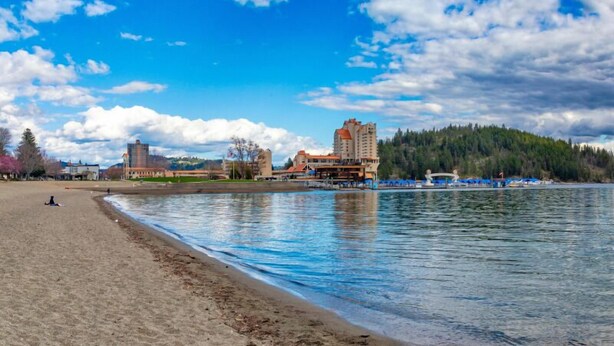 A waterfront hotel with a beach, a pier, and a forested hill in the background. - Experience luxury in this 800 sq. ft. King bed ADU in Downtown Coeur d (Coeur D Alene)