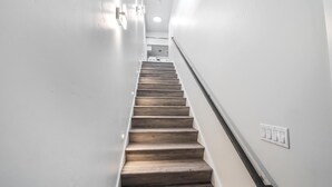A staircase with wooden steps, white walls, and a light switch on the wall. - Experience luxury in this 800 sq. ft. King bed ADU in Downtown Coeur d (Coeur D Alene)
