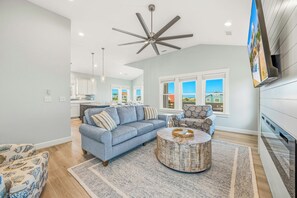 Ein Wohnzimmer mit einem blauen Sofa, einem runden Couchtisch und einem Deckenventilator.