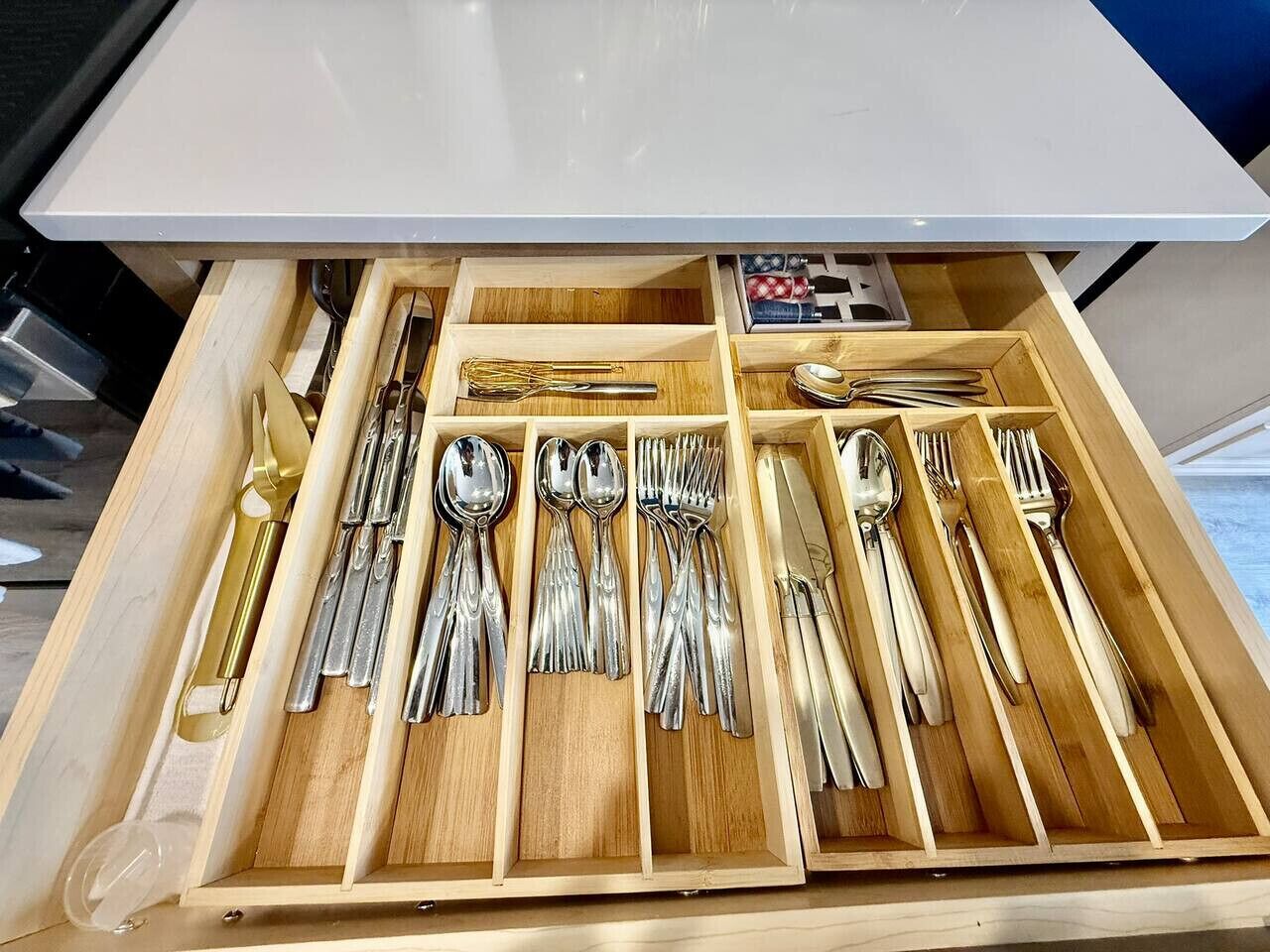 A drawer with neatly organized silverware, including spoons, forks, and knives.