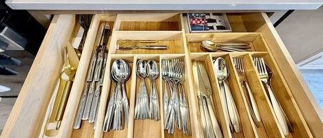 A drawer with neatly organized silverware, including spoons, forks, and knives.