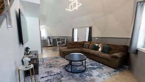 Uma sala de estar moderna com um sofá modular, uma mesa de centro redonda e um tapete estampado.