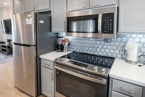 Cozinha moderna com eletrodomésticos de aço inoxidável, micro-ondas e fogão a gás.