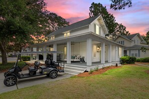 A two-story house with a covered porch, a golf cart, and a well-maintained lawn. - 1284 Laurel Grove 3 Bedroom Home (Miramar Beach)