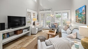 Ein Wohnzimmer mit Flachbildfernseher, zwei Sesseln, einer Couch, einem Couchtisch und einem Gemälde an der Wand.