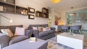A modern living room with grey sofas, a white coffee table, and a bookshelf. - Vacation Apartment 'Veras Home' with Sea View, Wi-Fi and Air Conditioning (La Tejita)