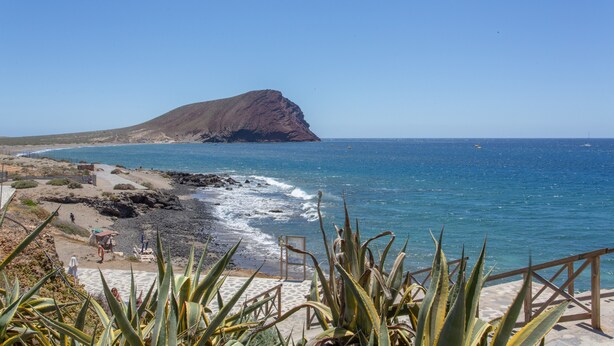 A coastal landscape with a rocky outcrop, a sandy beach, and a clear blue sea. - Vacation Apartment 'Veras Home' with Sea View, Wi-Fi and Air Conditioning (La Tejita)