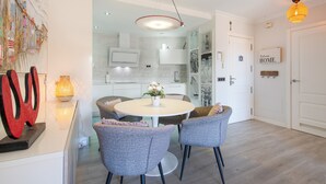 A modern kitchen with white cabinets, a round dining table, and grey chairs. - Vacation Apartment 'Veras Home' with Sea View, Wi-Fi and Air Conditioning (La Tejita)