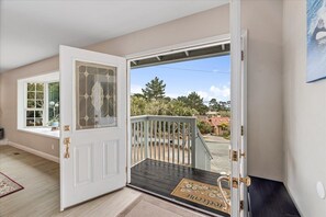 Une pièce avec une porte blanche, une fenêtre et une vue sur un jardin et des bâtiments à l’extérieur.