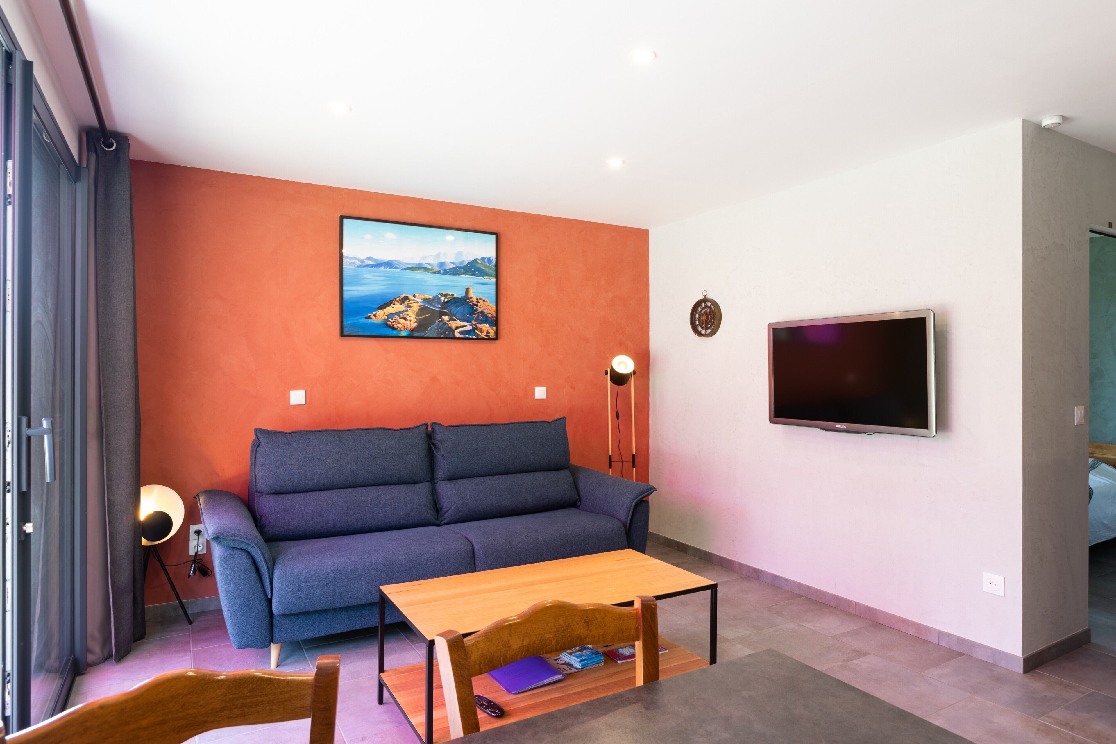 Una sala de estar moderna con un sofá, una mesa de centro, un televisor y un cuadro en la pared.