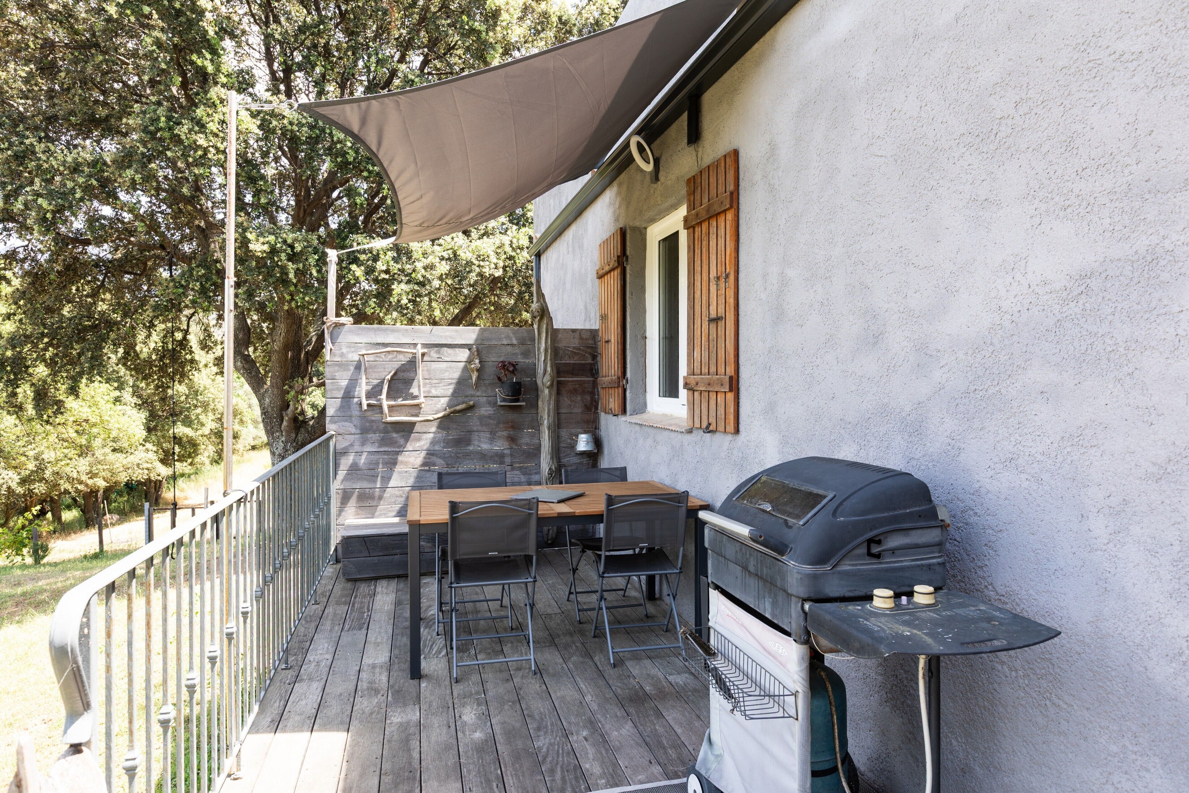 A wooden deck with a grill, outdoor seating, and a large canopy.