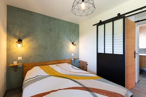 Ein Schlafzimmer mit einem Bett, zwei Wandleuchten, einem Holz-Kopfteil und einer Schiebetür.