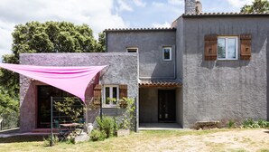 Una casa con facciata in pietra, un portico coperto e un giardino recintato.