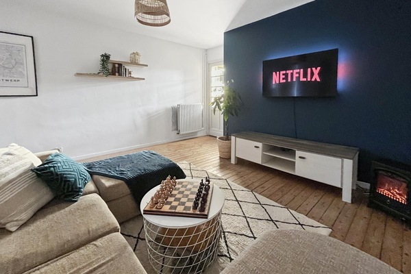 Bright and inviting living room with a comfortable sofa, large smart TV for streaming, and warm wooden floors. Natural light fills the space, while the cozy seating area and electric fireplace create a relaxed setting for unwinding after a day in the city