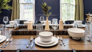 A dining table set with white plates, bowls, and cutlery, with a vase of greenery in the center. - 3000sqft 5B3.5B Retreat Near Lenovo Center - Upscale 3 King Beds (Cary)