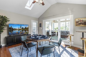 Una habitación con una gran televisión de pantalla plana, una mesa de póker y una zona de estar con sofá y sillones.