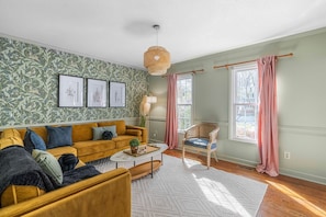 Una sala de estar con sofá, sillón, mesa de centro y pared con diseño.