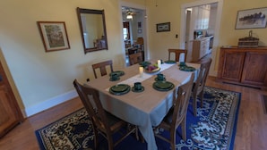 Comedor con una mesa dispuesta para cuatro, rodeada de sillas, y una cocina al fondo.