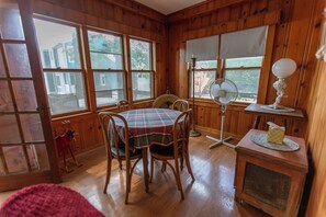 Un interior de madera con una mesa de comedor, sillas, un ventilador y una lámpara.
