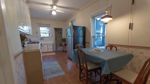 Una cocina con armarios de madera, un refrigerador y una mesa de comedor con sillas.