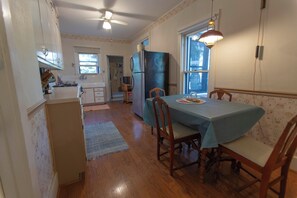A kitchen with wooden cabinets, a refrigerator, and a dining table with chairs. - 4-bedroom Lakefront Retro Cottage on Lake George in Fremont, IN (Fremont)