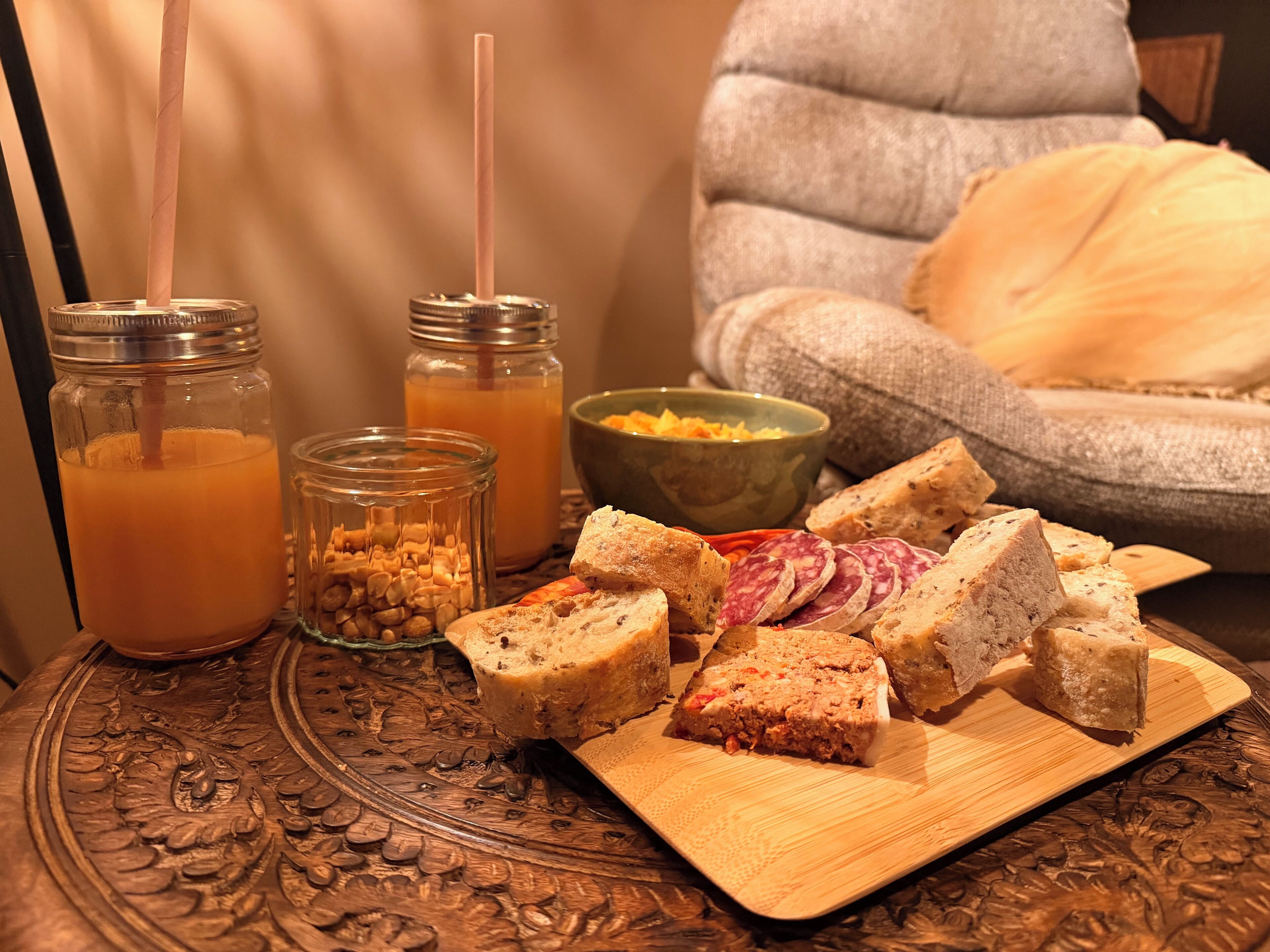A wooden table with food items, including sliced bread and a bowl of fruit.